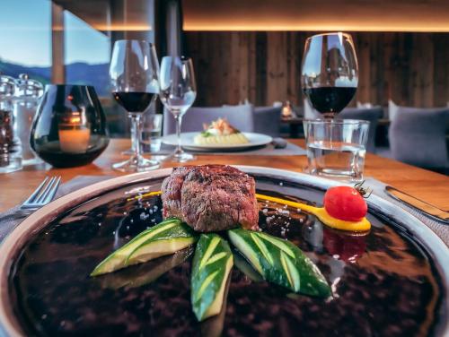 a plate of food on a table with wine glasses at ALMMONTE PRÄCLARUM SUITES Design Hotel in Wagrain