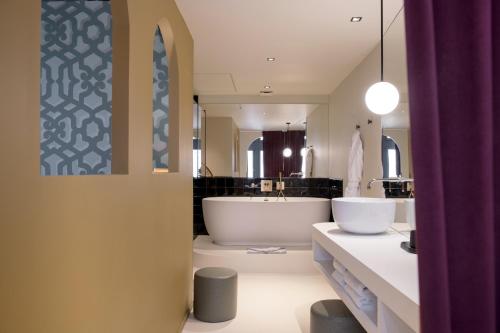 een badkamer met een groot bad en een wastafel bij MiHotel Tour Rose in Lyon