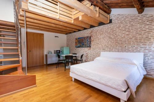 een slaapkamer met een wit bed en een bakstenen muur bij Loft Mirano Uno (Alloggi alla Campana) in Mirano