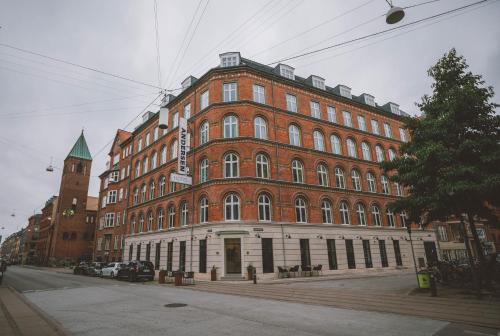 ein großes rotes Backsteingebäude mit einem Uhrturm in der Unterkunft Andersen Boutique Hotel in Kopenhagen