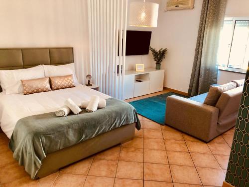 a bedroom with a bed and a chair and a television at Atlantic Luxury Apartment - Praia da Rocha in Portimão