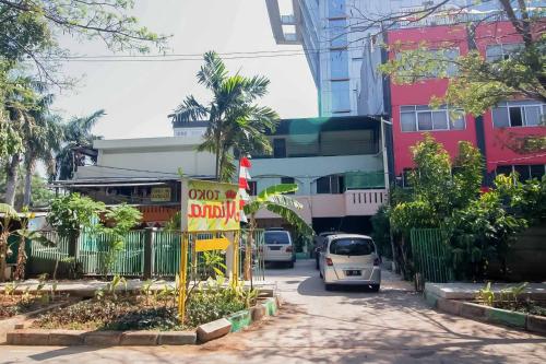 Miana Ancol Residence Mitra RedDoorz في جاكرتا: سيارة صغيرة تنزل على شارع المدينة بالمباني