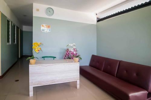 Miana Ancol Residence Mitra RedDoorz في جاكرتا: غرفة معيشة مع أريكة وساعة على الحائط