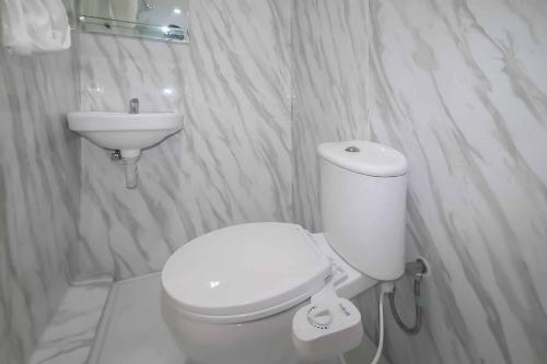 Miana Ancol Residence Mitra RedDoorz في جاكرتا: حمام ابيض مع مرحاض ومغسلة