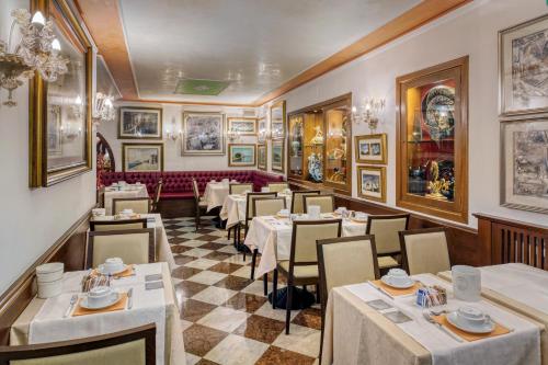 a restaurant with tables and chairs and paintings on the walls at Hotel Al Piave in Venice