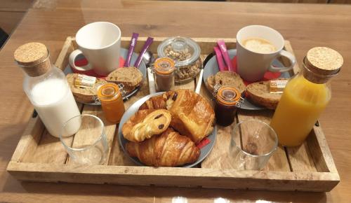 a tray with a plate of pastries and bottles of milk at Elle & Lui en Jacuzzi in Bernis
