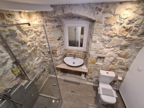 a stone bathroom with a sink and a toilet at NJ Corfu Liston Apartments in Corfu Town