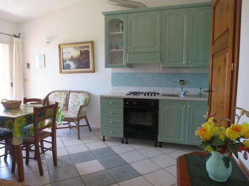 a kitchen with green cabinets and a table at Iocchedda in Porto Ottiolu