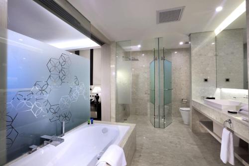 uma casa de banho com uma banheira e um chuveiro em vidro. em ASTON Kartika Grogol Hotel & Conference Center em Jakarta