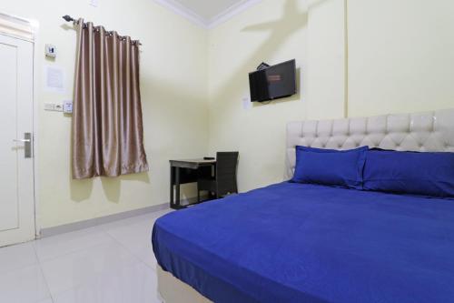 a bedroom with a blue bed and a television at Surya Homestay Pekanbaru in Pekanbaru