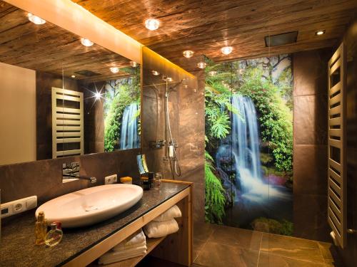 a bathroom with a sink and a waterfall mural at Aktivhotel Alpendorf in Sankt Johann im Pongau