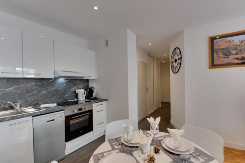 une cuisine avec des armoires blanches et une table et des chaises dans l'établissement Le Chevène - 2 or 4 person apartment with balcony in Annecy Centre, à Annecy