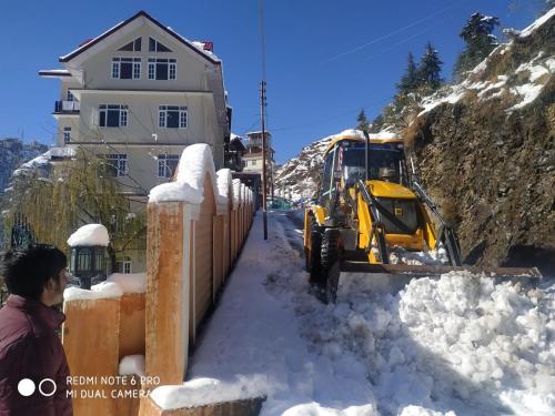 a bulldozer in the snow in front of a house at Sai Cottage Shimla in Shimla