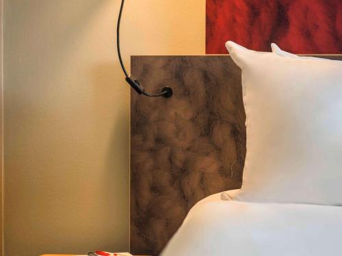 a bed with a white pillow and a lamp at Ibis Schiphol Amsterdam Airport in Badhoevedorp