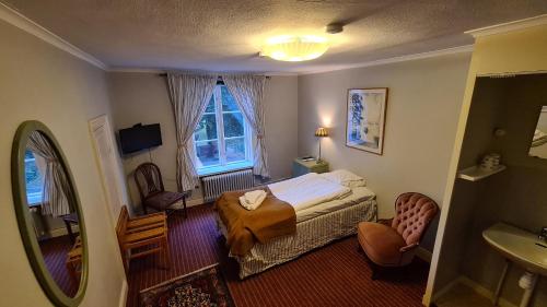 a bedroom with a bed and a sink and a mirror at Kolbäcks Gästgivaregård in Kolbäck