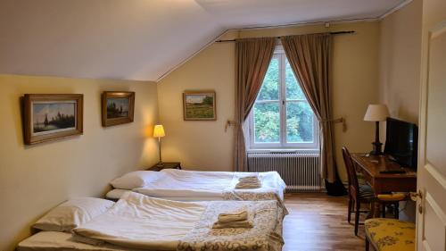 a bedroom with two beds and a desk and a window at Kolbäcks Gästgivaregård in Kolbäck