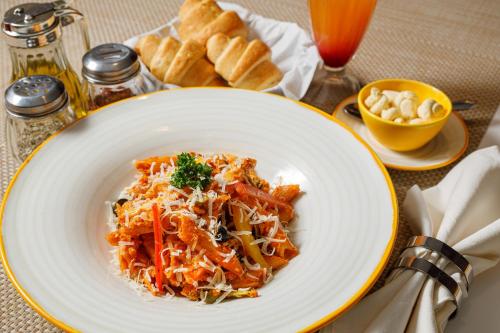 a plate of food with pasta and bread on a table at The Riverview Retreat Corbett by Leisure Hotels in Garjia