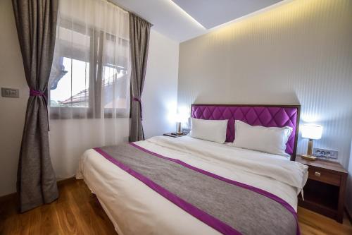 a bedroom with a bed with a purple headboard and a window at Apartmani Buket Zlatibor in Zlatibor