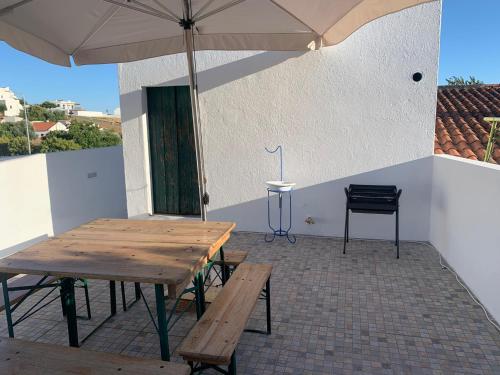 a patio with a wooden table and an umbrella at Casa da Avó Maria Ana in Arraiolos