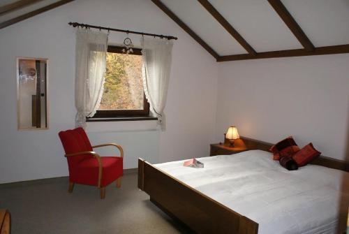 1 dormitorio con cama, silla roja y ventana en Haasenhaus, en Hinterstoder
