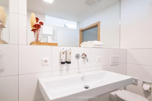 a white bathroom with a sink and a mirror at Schlosshotel Horneck in Gundelsheim