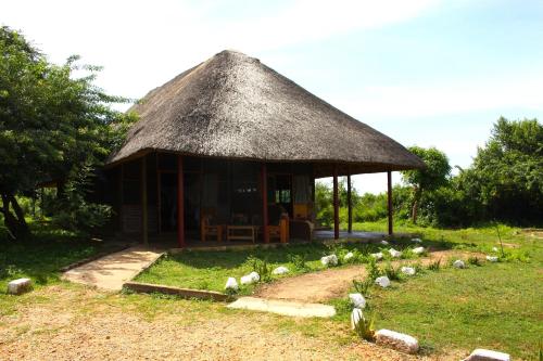 a hut with a grass roof and a bunch of animals at Red Chilli Rest Camp in Murchison Falls National Park