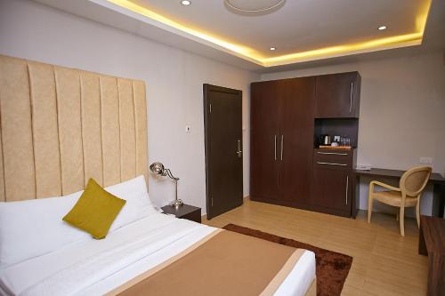 a bedroom with a bed and a desk and a kitchen at The Cabin Hotel in Accra