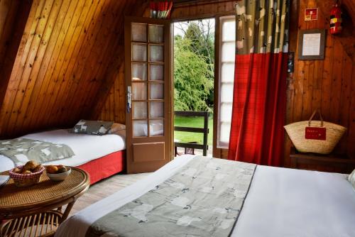 a bedroom with two beds and a table and a window at Logis Le Vieux Logis in Lestelle-Bétharram