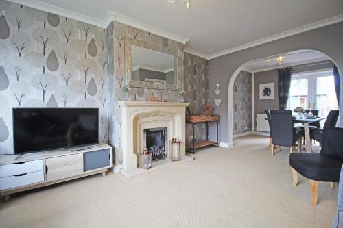 a living room with a television and a fireplace at Queens Road - Luxury Spacious Home in Chester in Christleton