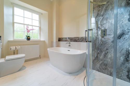 een badkamer met een groot wit bad en een douche bij Bankton House in Livingston