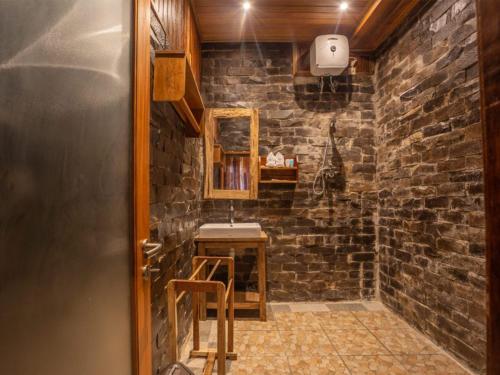 Baño de piedra con lavabo y espejo en Bali Jegeg Munduk Hotel, Bar, and Restaurant, en Munduk