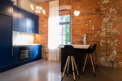 een keuken met blauwe kasten en een bakstenen muur bij Central Park Residence in Keyla
