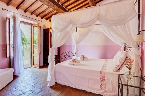 a bedroom with a white bed with a canopy at Podere Lamino in Monticchiello