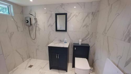 a white bathroom with a sink and a toilet at The Garden Room, 1 Heath Cottage in Knutsford
