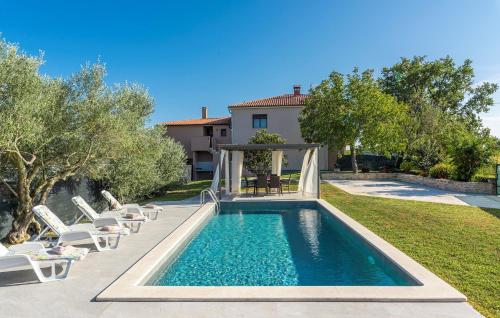 a swimming pool in a yard with chairs and a house at Terre Bianche with Private Pool and Whirlpool in Buje