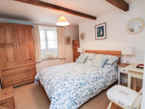 a bedroom with a bed and a desk and a window at Crosscombe Barn in Kingsbridge