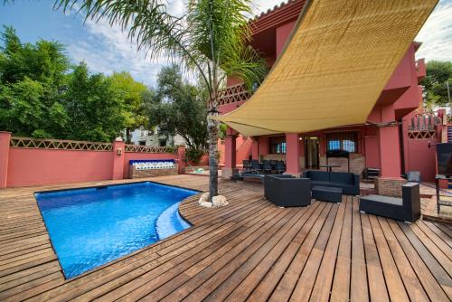 een houten terras met een zwembad op een huis bij Holidays2Malaga Candado House pool & garden in Málaga