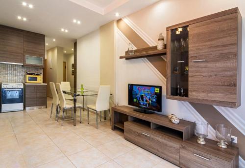 een woonkamer met een televisie en een tafel met stoelen bij Kountouriotou New Quiet and Central apartment in Athene
