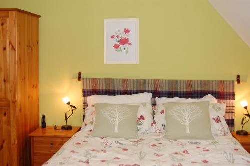 1 dormitorio con 1 cama con 2 almohadas en Donmar Cottage en Skeabost