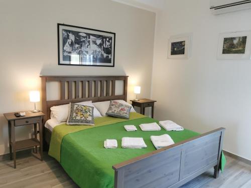 sypialnia z zielonym łóżkiem i 2 ręcznikami w obiekcie B&B CESARE'S Guests w mieście Aci Trezza