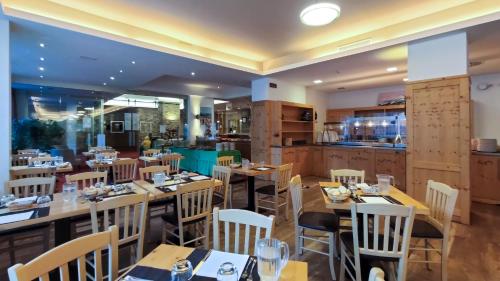 un ristorante con tavoli e sedie in legno e una cucina di Hotel Principe Marmolada a Malga Ciapela