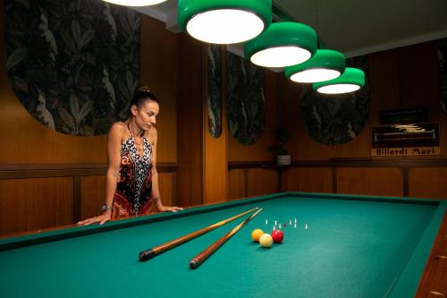 a woman standing next to a pool table at Hotel Rosa in Lido di Jesolo