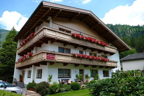 マイヤーホーフェンにあるGästehaus Hochmuthの赤い花が咲くバルコニー付きの建物
