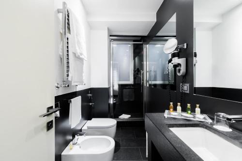 Baño en blanco y negro con aseo y lavamanos en Hotel Mancino 12 en Roma