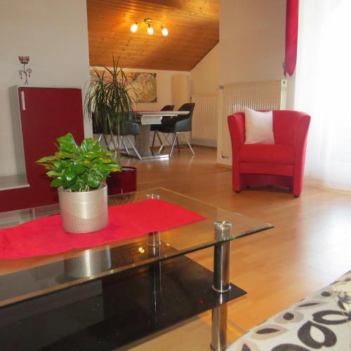 a living room with a red chair and a table at Wohlfühlapartment Erlenberg in Thurmansbang