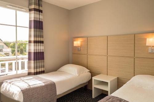 a hotel room with two beds and a window at Les Villas du SPA in Pléneuf-Val-André