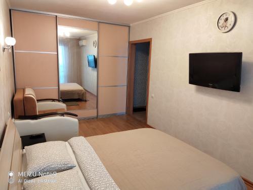 マグニトゴルスクにあるApartment on the Green Log 33 1のベッドとテレビが備わるホテルルームです。