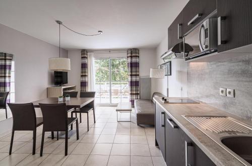 - une cuisine et une salle à manger avec une table et des chaises dans l'établissement Les Villas du SPA, à Pléneuf-Val-André