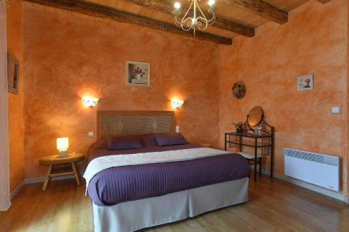 a bedroom with a bed in a room with orange walls at Le Mas de La Pommeraie in Saint-Géry