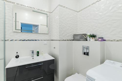W łazience znajduje się umywalka, toaleta i lustro. w obiekcie Apartament36-1c Calamo Park w Olsztynie